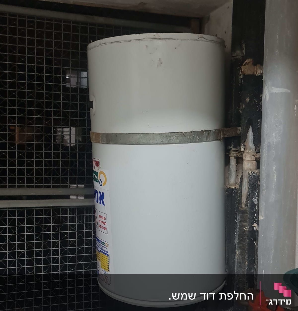 דוד שמש לבן מותקן על קיר עם צינור מתכת